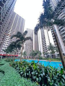 a pool with palm trees in front of tall buildings at Sky House BSD By Micky Studio in Cilenggang