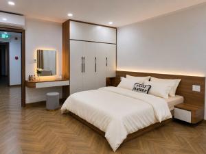 a bedroom with a large white bed and a mirror at EcoCity Suites BMT in Buôn Enao