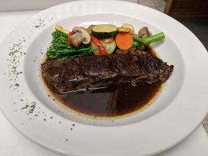 a plate of food with meat and vegetables on a table at Laughing Horse Lodge in Bigfork