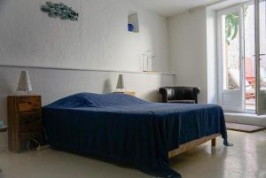 a bedroom with a blue bed with a chair and a window at Au coeur de Leucate in Leucate
