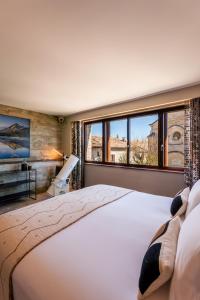 a bedroom with a large bed and a large window at La Maison du Passage - Chambres - Suites premium, Spa, Piscine et Restaurant in Martignargues
