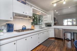 a kitchen with white cabinets and a stove top oven at Lillie by the Sea in Summerland +11 photos