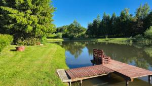a bench sitting on a dock next to a pond at Pole u Daniela in Grzybina