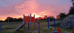 a playground with a slide in a field with a sunset at MODERN APARTAMENT Walendów Park in Walendów