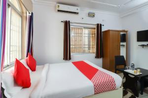 a bedroom with a bed with red pillows and a desk at Capital O The Tulip in Rānchī