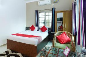 a bedroom with a bed with red pillows and a chair at Capital O The Tulip in Rānchī