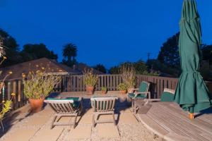 a patio with a table and chairs and a green umbrella at Magnolia Cottage in Santa Barbara