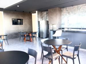 a restaurant with tables and chairs and a kitchen at Studio in Barbacena