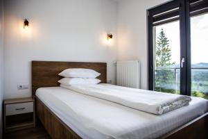 a bedroom with a bed with white sheets and a window at Cabana The One in Beliş