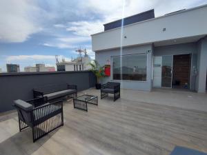 a rooftop deck with chairs and a bench on a building at Studio in Barbacena