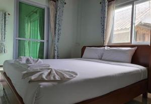 a bedroom with a bed with white sheets and a window at Baan Ton Pai in Ko Yao Noi
