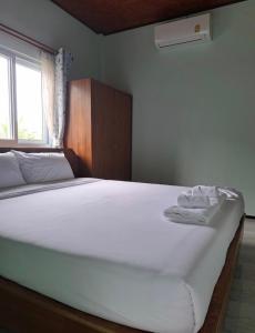 a large white bed in a room with a window at Baan Ton Pai in Ko Yao Noi