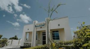 a white building with a palm tree in front of it at Maisara lodge in Kilindoni
