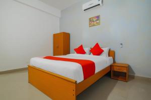 a bedroom with a large bed with red pillows at Hotel O The Goan Courtyard in Goa +26 photos