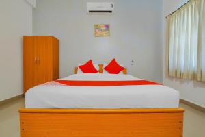a bedroom with a large bed with red pillows at Hotel O The Goan Courtyard in Goa