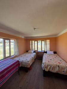 two beds in a room with windows at Kusikuy Wasy Lodge in Puno