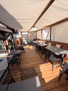 a restaurant with tables and chairs on a wooden deck at Hotel De Paris in Poligny