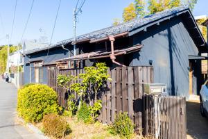 a blue building with a fence next to a street at Takeno-an in Mitaka