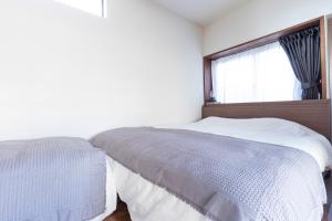 a white bedroom with a bed and a window at Takeno-an in Mitaka
