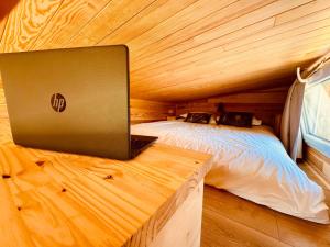 a laptop computer sitting on a bed in a wooden room at l'échappée verte in Anvéville