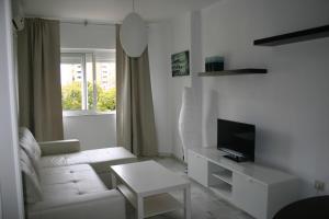 sala de estar blanca con sofá blanco y TV en Apartamento Las Adelfas, en Jerez de la Frontera