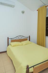 a bedroom with a large white bed with yellow pillows at Mango Villa in Kengalla