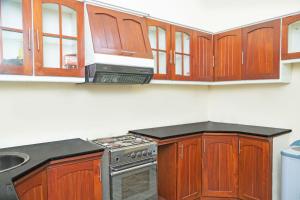 a kitchen with wooden cabinets and a stove at Mango Villa in Kengalla