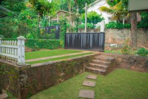 a garden with a stone wall and a fence at Mango Villa in Kengalla