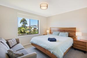 a bedroom with a bed and a couch and a window at Seaside Escape in Tathra
