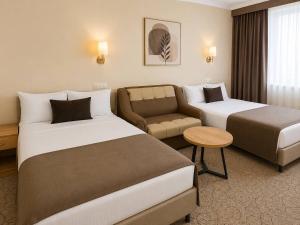 ein Hotelzimmer mit zwei Betten und einer Couch in der Unterkunft Vila Verde in Chişinău