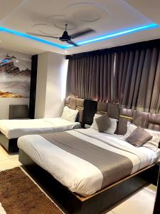 two beds in a hotel room with blue lights at Hotel prime View in Ahmedabad