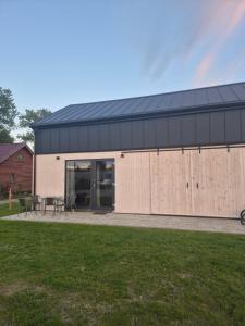 a building with a black roof and wooden doors at Domki letniskowe Hamer in Łeba
