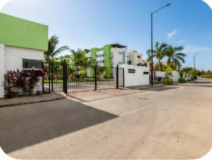 a fence in front of a building with palm trees at El descanso del guerrero in Barra Vieja