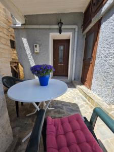 a table with a vase of purple flowers on a patio at Sidirounta Traditional Home 2 in Chios