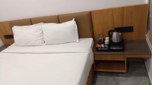 a bed with white sheets and a table with a coffee maker at Hotel Dwarkesh in Dwarka