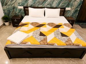a bed with a colorful quilt on it at Shri Shyam Kunj Hotel in Ambikāpur