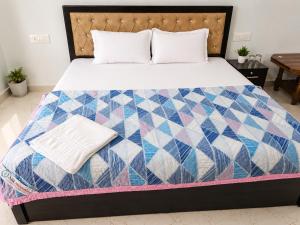 a bed with a colorful quilt on it at Shri Shyam Kunj Hotel in Ambikāpur