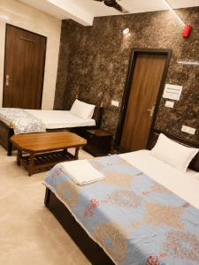 a room with two beds and a table in it at Shri Shyam Kunj Hotel in Ambikāpur