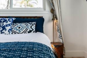 a bed with blue and white pillows and a window at Bella Blu in Avila Beach
