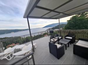 a patio with chairs and tables and a view of the water at Apartman G 60 in Meljine