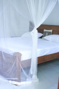 a bedroom with a bed with white mosquito netting at Nela House in Galle