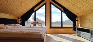 a bedroom with a bed in a room with windows at Mazurska Puszcza domek pod klonem z balią ogrodową in Budy