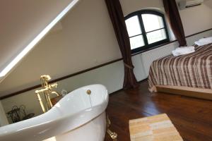 a bathroom with a white bath tub and a bed at Hotel Vinohrad in Milotice