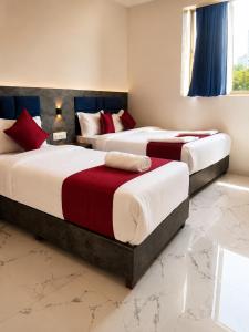 two beds in a room with red and white at Transit Seven Hills Hotel Near Airport Mumbai T2 in Mumbai