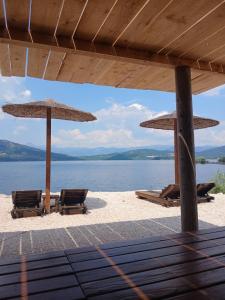 two umbrellas and chairs on a beach with the water at Apartmani Janjusevic in Nikšić