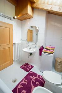 a bathroom with a sink and a toilet and a rug at Tinnerhof in Appiano sulla Strada del Vino