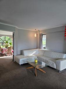 a living room with a white couch and a glass table at Amore Manor Auckland in Auckland