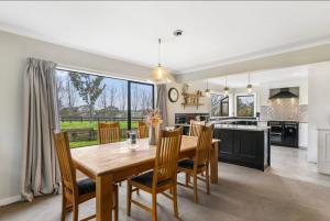 a kitchen and dining room with a wooden table and chairs at Amore Manor Auckland in Auckland