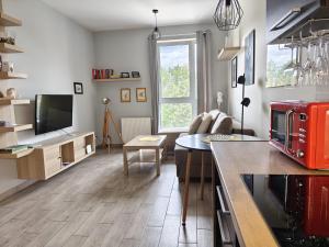 a kitchen with a living room with a table and a couch at Apartament Glatz - na Letniej, Kłodzko, winda, garaż podziemny, balkon z widokiem na góry in Kłodzko