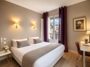 a bedroom with a large white bed and a window at Hôtel Cardinal in Rouen